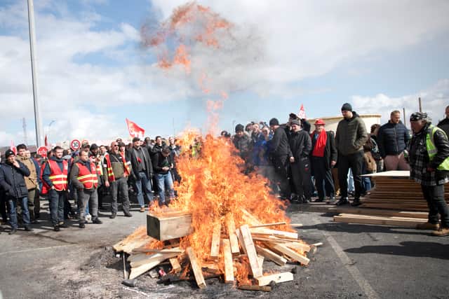 Striking employees gather around a fire outside Gronfreville-l'Orcher refinery on March 24, 2023