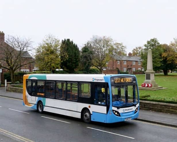 Stagecoach bus drives past a war memorial