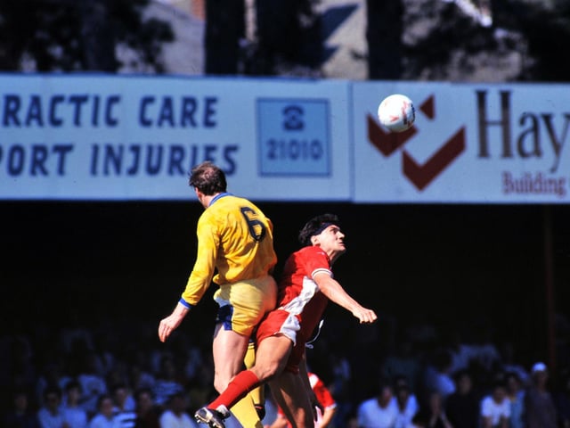 Peter Haddock rises high to clear the ball under pressure from Bournemouth's Kevin Bond.