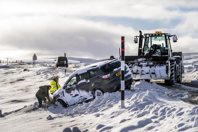 People work, in snow conditions, to pull a car back on to the road on the Buttertubs Pass in North Yorkshire on Sunday November 28