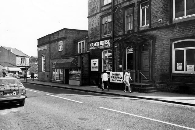 Pudsey's Manor House Street in April 1982 showing, from left, Barclays Bank, then W.H. Bowman, butchers, Manor House insurance consultants including the local office of the Woolwich Building Society, and on the right the offices of St. John's Ambulance Brigade. In the background on the left the junction with Lowtown can be seen, with shops including G.W. Marsh, TV rental.