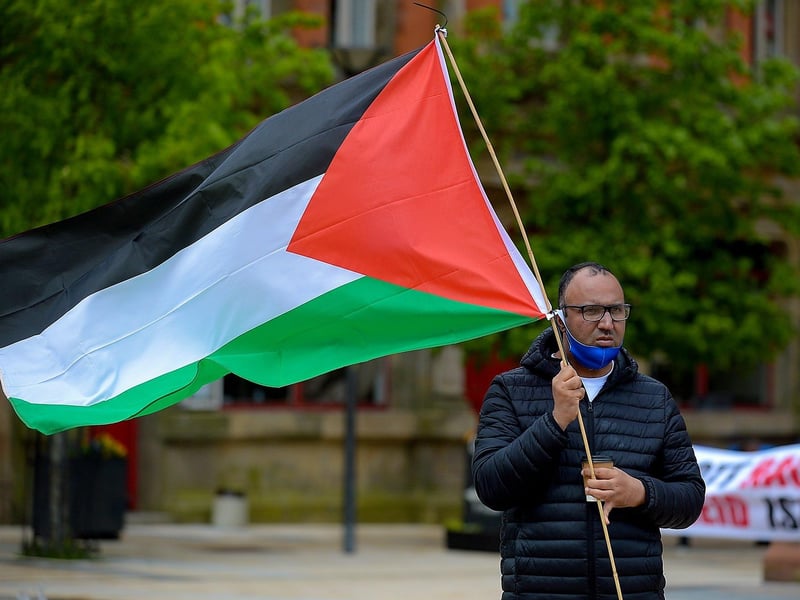 Sameh, from Egypt, waves a Palestinian flag during Saturday afternoon‘s rally, at Guildhall Square, in solidarity with the people of Palestine. Photo: George Sweeney. DER2119GS – 020