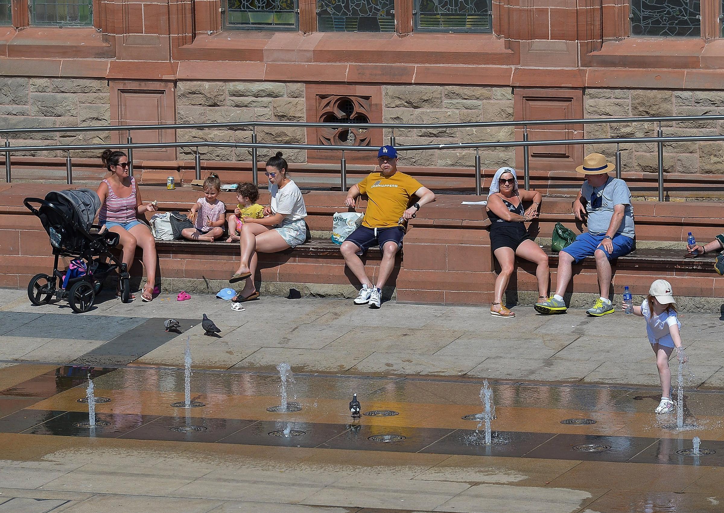 People relax in in the sun in Guildhall Square during the recent mini heatwave. DER2129GS - 064