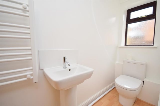 The ground floor of the Ravenshead property also features this cloakroom. It contains a low-level WC, pedestal wash basin, heated towel-rail and laminate flooring.