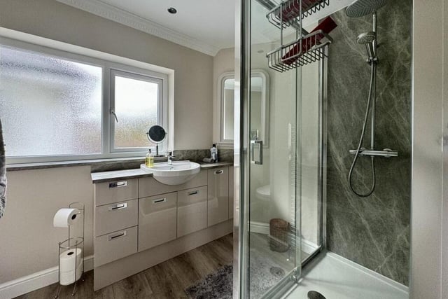 The second bedroom has access to this en suite shower room, which is fitted with a large shower cubicle, a wash hand basin set into a vanity unit with in-built storage, a WC, a  storage cupboard and a chrome, heated towel-rail.