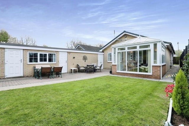 This photo shows not only the conservatory jutting out at the back of the bungalow but also, to the left, a modern external office and storage room, which are connected to a triple-length garage in a building that has a recently fitted fibreglass roof.