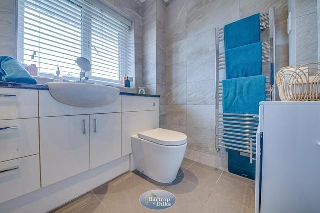 The family bathroom has a touch of luxury about it, especially with its tiled floor and walls. It also includes a wash hand basin, set within a vanity unit, a low-flush WC and a heated towel-rail.