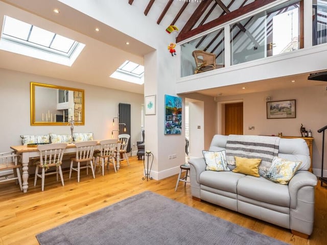 Another shot of the bright and modern family room, which also has space for a dining area. The floor is wooden.