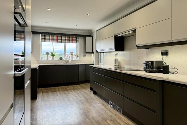 Into the contemporary kitchen, which has been fitted with a range of wall and base units, an induction hob with extractor fan above, dishwasher and washing machine.