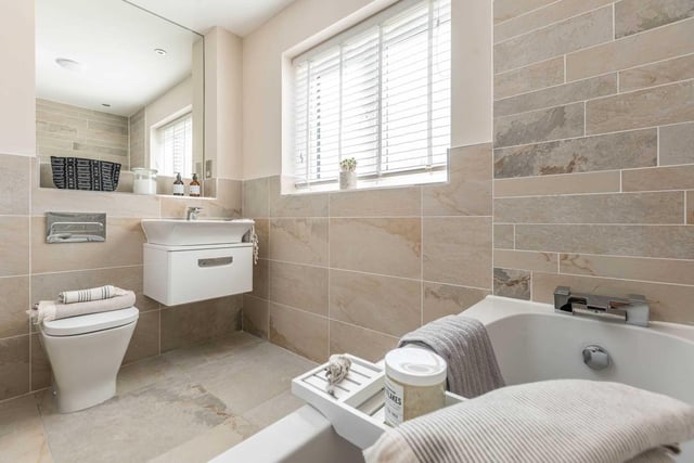 A modern and tiled bathroom complete with a large window.