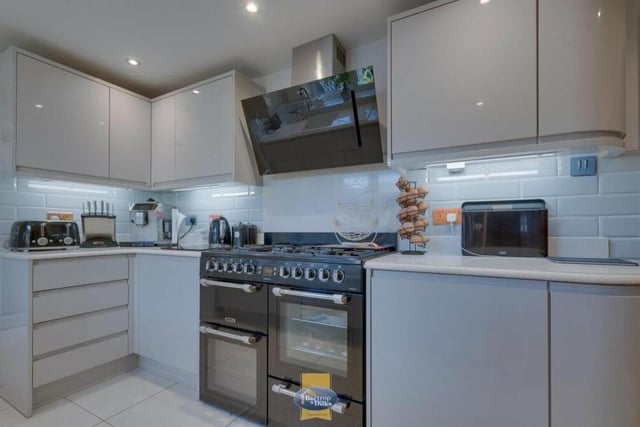 Among the integrated appliances within the kitchen are a range cooker with hob, and a dishwasher. The floor is tiled.