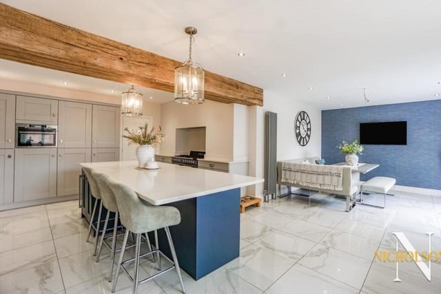 An overview of the kitchen and dining room. A central island, with breakfast bar and quartz work surface, is an attractive feature of the kitchen, as is a range of wall and base units with quartz work surfaces incorporating a ceramic sink unit and mixer tap.