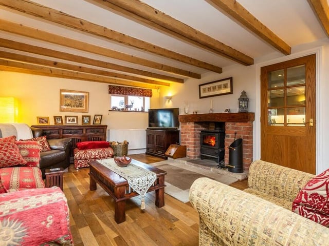 Moving on now to the large sitting room, which is another admirable asset on the ground floor. Note its wonderful beamed ceiling and open fireplace with an inset, cast-iron, log-burning stove.