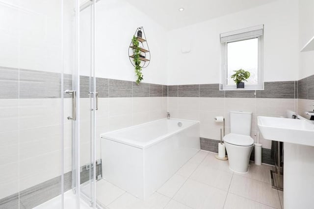 The family bathroom at the Blackstone Drive house is fitted with a four-piece suite that consists of a bath, enclosed corner shower, wash hand basin and WC. The floor is tiled.
