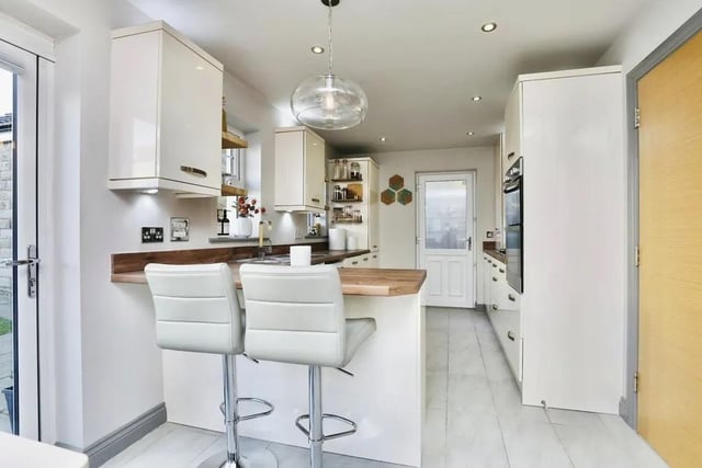 A last look at the open-plan kitchen, which has a breakfast bar with space for chairs. There is also a built-in storage cupboard, spotlights to the ceiling and a door leading to the side if the £425,000 property.