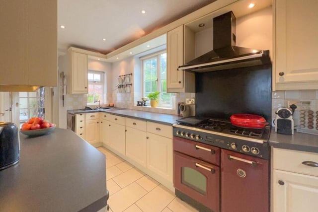 Integrated appliances in the kitchen include a free-standing range-style gas cooker with electric extractor fan above, dishwasher and fridge/freezer. Windows overlook, and a door leads out to, the garden.