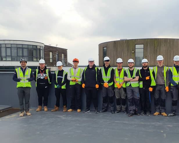 Students from North Notts College standing on the roof of the new building, accompanied by a representative from VINCI Building.