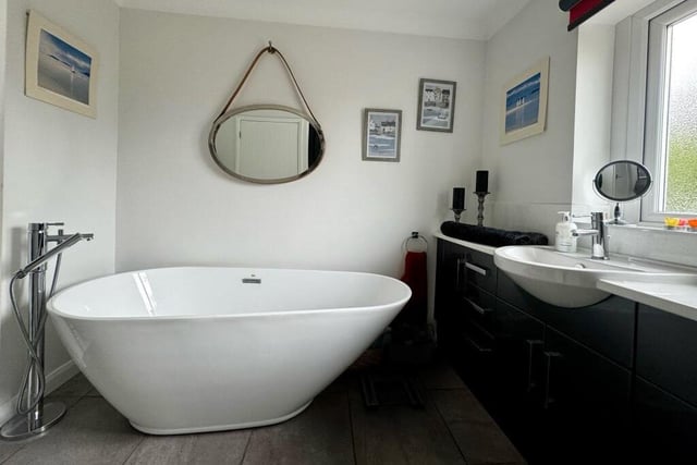 This contemporary, free-standing bath is a notable feature of the family bathroom, which also has a tiled floor and a heated towel-rail.
