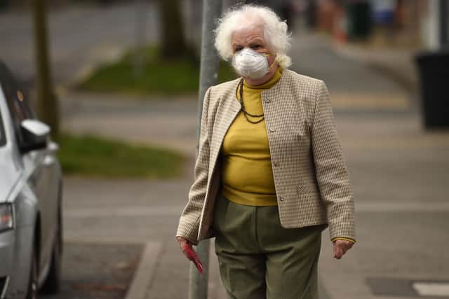 An elderly woman wearing a protective face mask leaves a newsagents (Photo by OLI SCARFF/AFP via Getty Images)