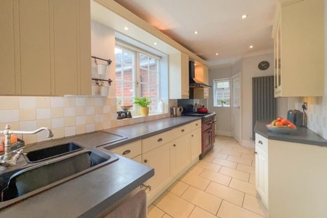 A spacious kitchen is fitted with an extensive range of wall and base units, with complementary work surfaces incorporating a sink unit with mixer tap. Downlights, coving to the ceiling, a tiled floor and a modern, vertical central heating radiator all add splashes of style