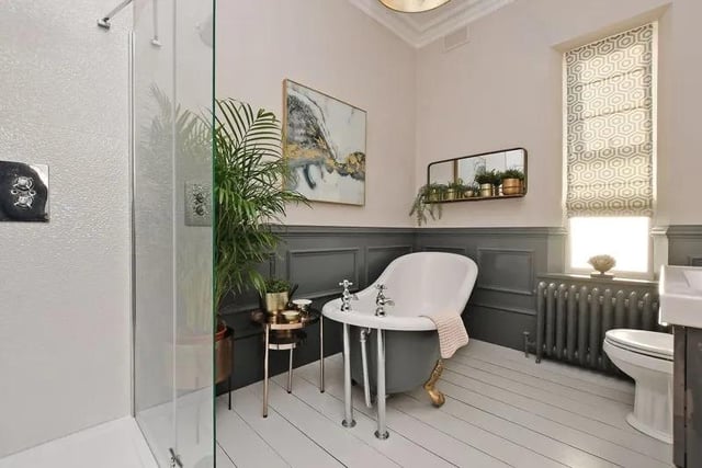 The bathroom would not be out of place in a magazine. There is a Victorian styled freestanding bath, a shower enclosure with a glass screen, a vanity wash basin, WC, finished with a blend of paneled walls and fashionable tiling.