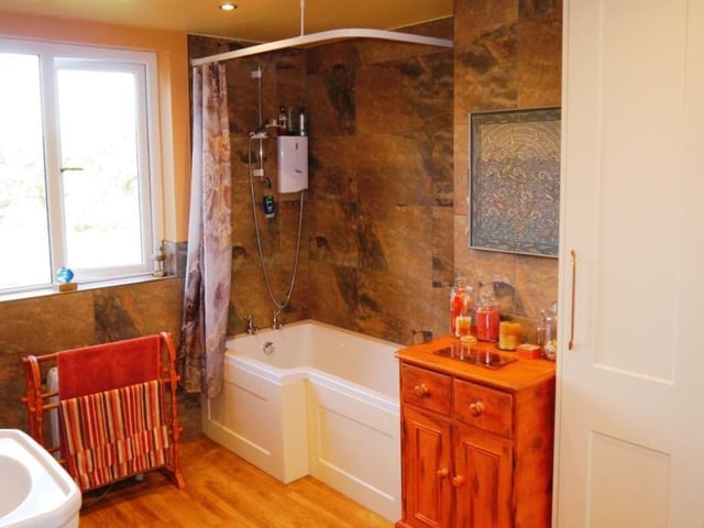As we move up to the first floor at the Turnerwood cottage, the first room we come across is this neat bathroom. It is fitted with a three-piece suite comprising a panelled bath, with independent electric shower over, pedestal wash hand basin and low-level WC.