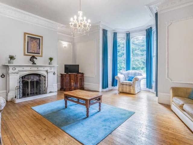 To the left of the reception hall is this delightful drawing room, with its high ceilings, open fireplace, oak flooring and imposing bay window. Comfortable and classy, it is infused with natural light.