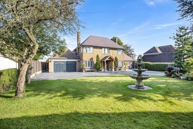 A last look at the formidable frontage of the house, with a water feature on the lawn to the right, a solid oak porch protecting the entrance to the centre and the attached double garage to the left.
