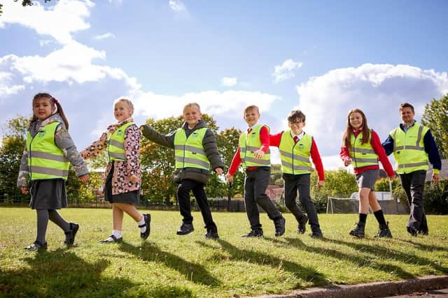 Chris Carlin, marketing manager Miller Homes Yorkshire, gives high-vis vests to children from Harworth Primary School