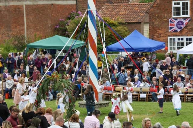 Children dancing round the maypole at Wellow's annual event watched by large crowds