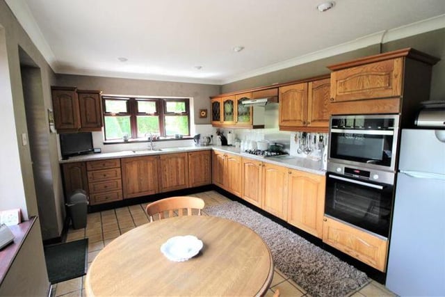 The kitchen is fitted with a range of wall and base units and rolltop work surfaces with inset sink, drainer and mixer tap. It also features a tiled floor, dual-aspect windows and doors leading to a utility room and the dining room.