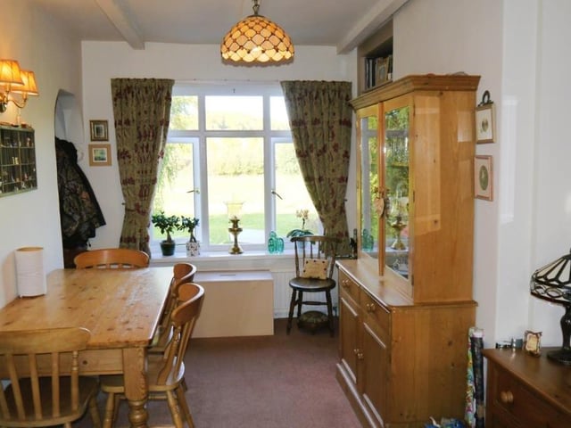 The delightful dining room is at the back of the cottage and offers open views of the countryside. Stairs lead down to the kitchen, which can be found in the basement.