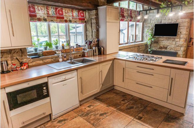The large kitchen/diner has original beams, ceramic floor tiles and a range of kitchen units.