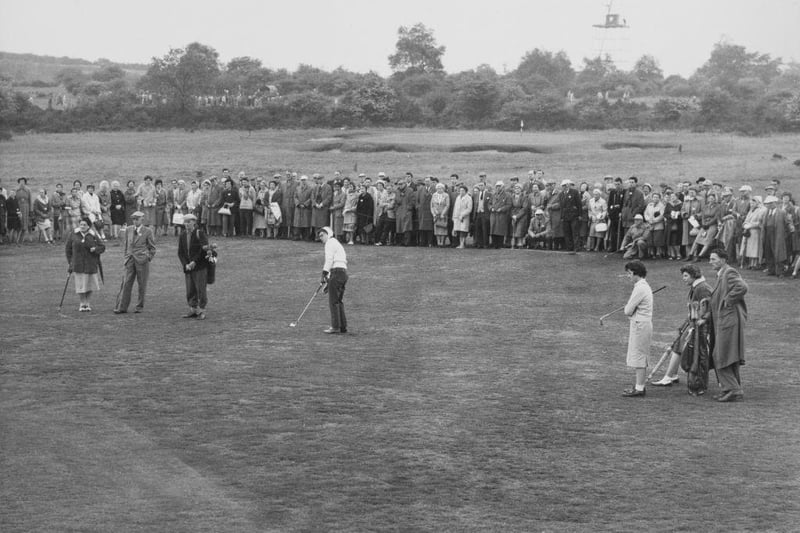 A crowd of spectators watch as Anne Quast of the United States chips off the fairway to the 12th green during her singles match against Janette Robertson of the Great Britain & Ireland team at the 11th Curtis Cup Match golf competition on 21st May 1960 at the Lindrick Golf Club in Worksop.