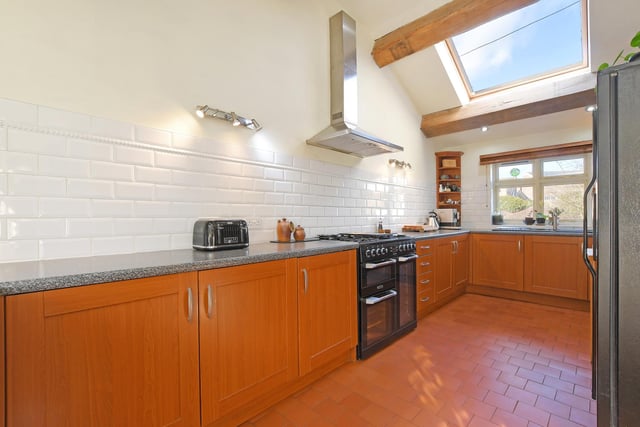A light and airy kitchen which has a vaulted ceiling with Velux roof window and exposed timber beams. There’s a range of fitted base and wall units incorporating matching work surfaces, tiled splash backs and an inset bowl sink with a chrome mixer tap. Appliances include an integrated Baumatic fridge and a Leisure Cuisinemaster range cooker with a four-ring gas hob, wok burner, two ovens, grill and extractor hood over.