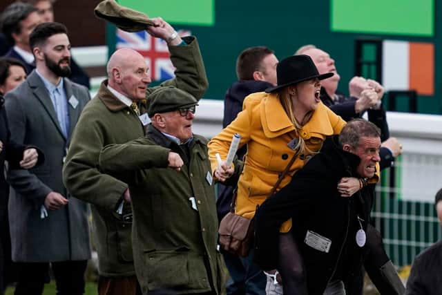 The Cheltenham Festival attracts all types of people - and all types of celebration! Here, they are cheering home their horse as a race unfolds on one of the track's giant TV screens.