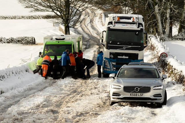 People help to push an Asda delivery van stuck on the A515 in the Derbyshire Peak District.