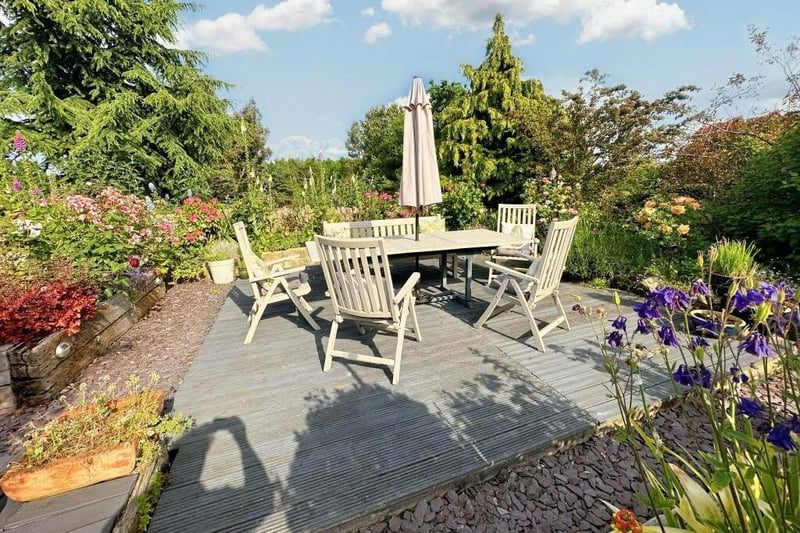 Surrounded by plants, trees and flowerbeds, this patio area is a pleasant spot to relax in the summer or spring sunshine.