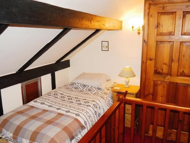 The second bedroom sits on the second floor. It includes a fitted carpet, ceiling with exposed beams, a double-glazed Velux window and three wall-light points.