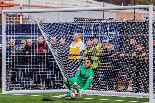 Seb Malkowski saves a penalty in the shoot-out against Ramsbottom.