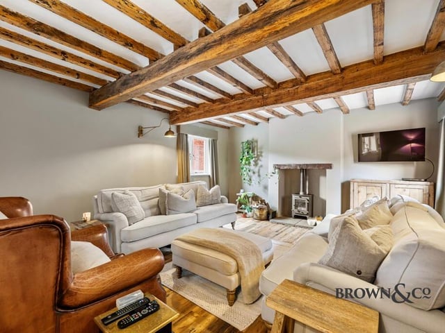 A lovely light lounge with cosy stove and wooden beams to the ceiling.