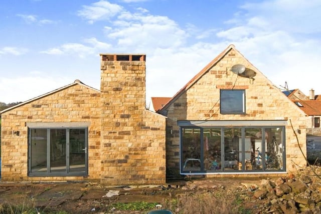 An exterior view of the barn conversion, with large windows and doors overlooking, and giving access to, the wraparound garden.