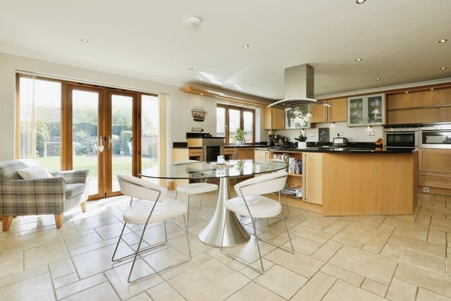 The kitchen, with its tiled floor and downlights, has ample space for a dining or breakfast table, while doors open out to the attractive garden.