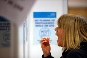 A woman uses a swab to take a sample from her mouth at a NHS Test and Trace Covid-19 testing unit (Photo by ADRIAN DENNIS / AFP) (Photo by ADRIAN DENNIS/AFP via Getty Images)