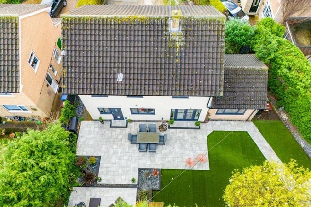 This revealing aerial shot shows the rear of the £350,000 property, with its lawn, patio area, French doors leading from the breakfast kitchen and extension to the right forming the dining room.