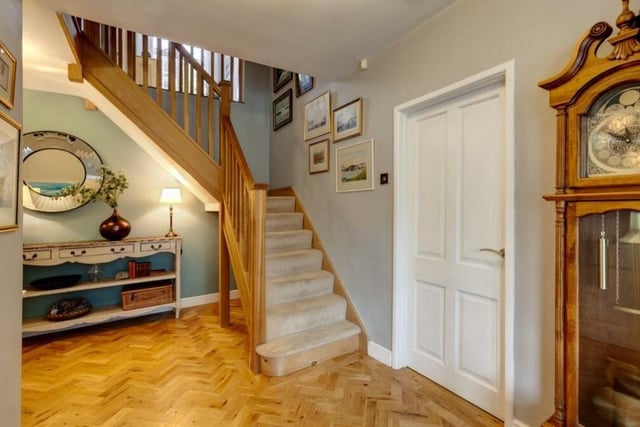 The entrance vestibule leads to this inviting hallway, which has a herringbone oak floor and an oak staircase, with hand-rail and balustrade, that rises to the first floor.