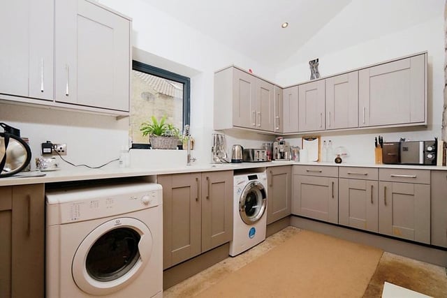 The property features both a generously-sized kitchen, with partially fitted wall and base units, and also a handy utility room with space and plumbing for a washing machine and additional appliances. The utility room has an ample range of storage cupboards, a sink with tap and a work surface area.