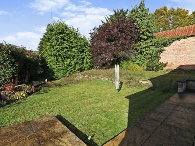 The garden includes patio areas, paved walkways, flowerbeds and shrubs.