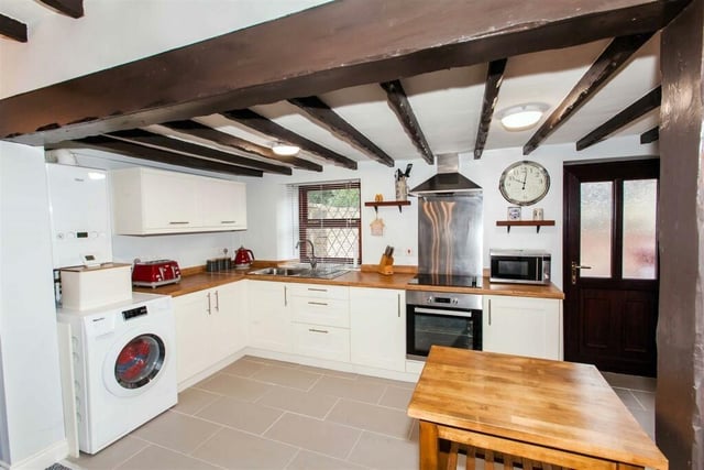 The kitchen area has a range of fitted storage cabinets with wooden worktops and an integrated oven and hob.