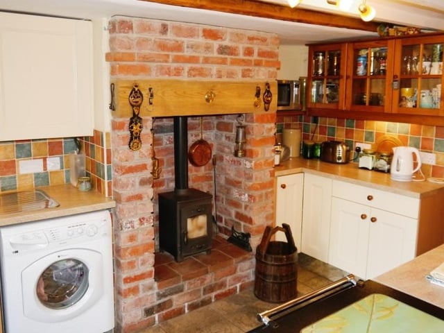 Like the lounge, the characterful kitchen also has an inglenook fireplace with brick-built surround and a cast-iron, multi-fuel burning stove.